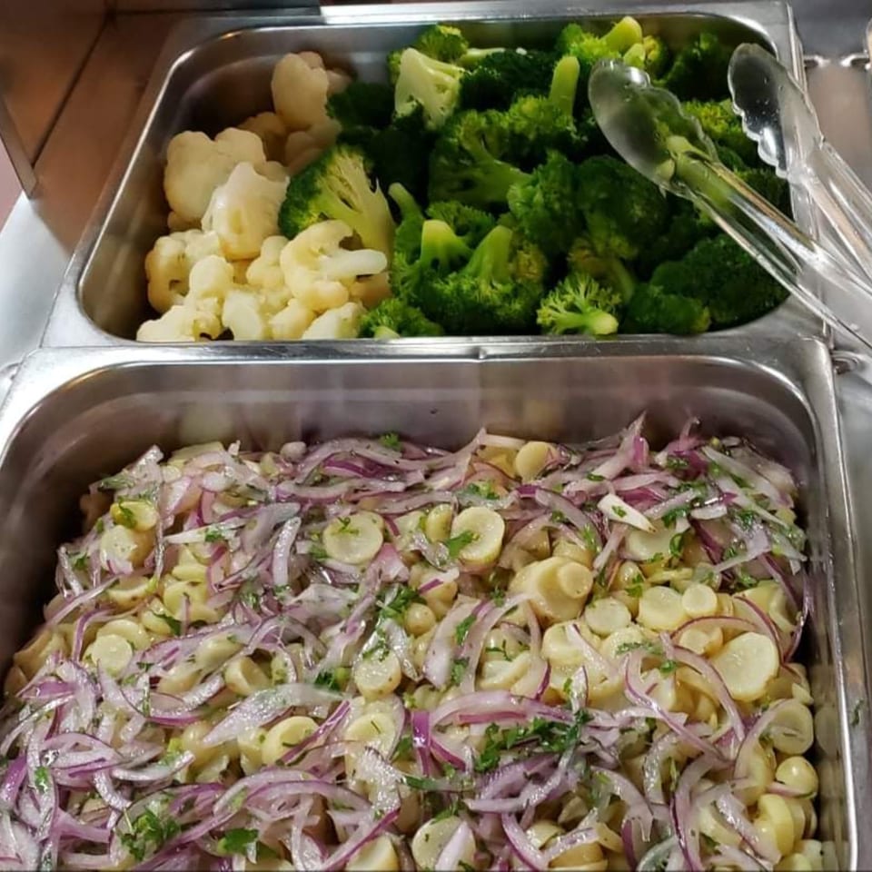 Buffet trays with steamed broccoli, cauliflower, and a salad of hearts of palm with red onions.